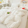 A white quilted duvet cover and pillow set displayed on a bed, with a small stuffed animal nearby.
