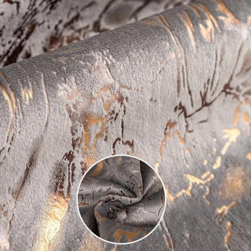 Close-up of a gray velvet cushion cover with abstract gold foil leaf patterns.