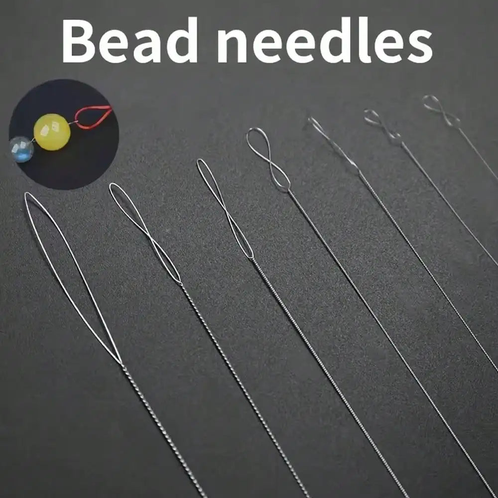 A collection of silver bead needles and a small yellow bead are displayed on a dark surface.