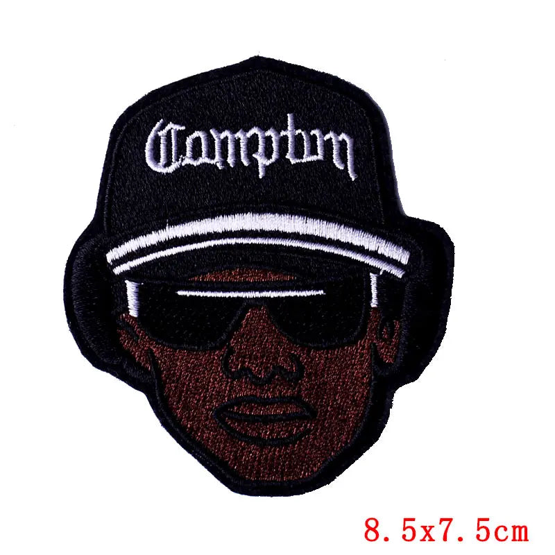 Black embroidered patch featuring a stylized skull design with white text on a black baseball cap background