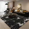 A black and white geometric non-slip area rug is displayed in a modern living room setting.
