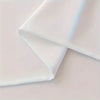 White fabric tablecloth folded diagonally on a light surface.