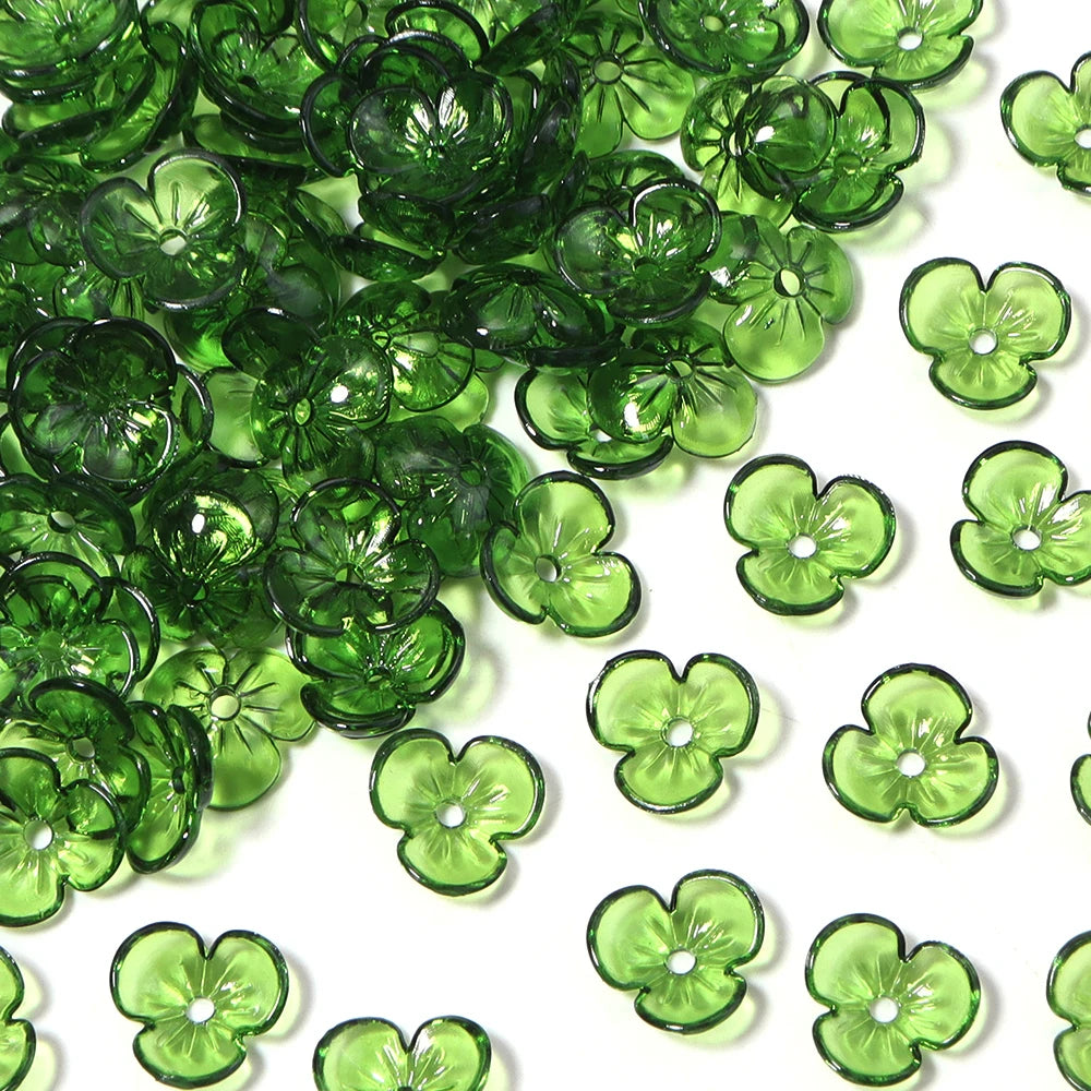 Green resin flower bead caps scattered on a white background for jewelry making