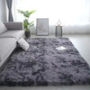 A gray fluffy rug in a living room with a window and potted plant.