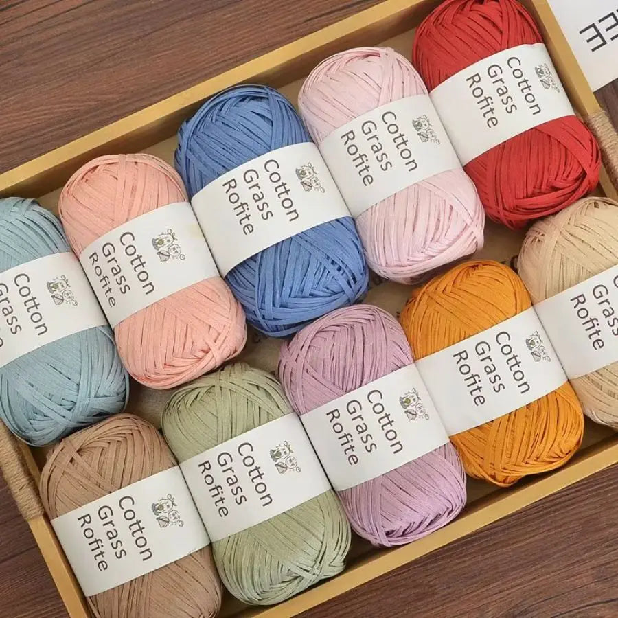 A box of natural cotton grass yarn in various shades including blue, pink, orange, and beige.