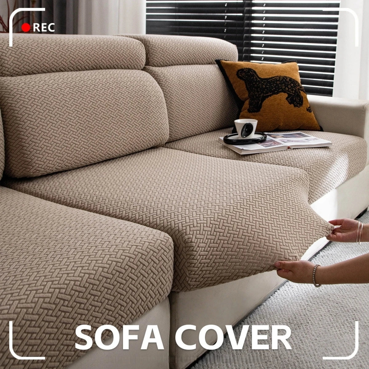 A beige stretchy polar fleece sofa cover is shown on a modern sectional sofa with a dark accent pillow.