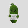A handmade plush pocket doll shaped like a green pickle with a smiling face and an emotional support message tag.