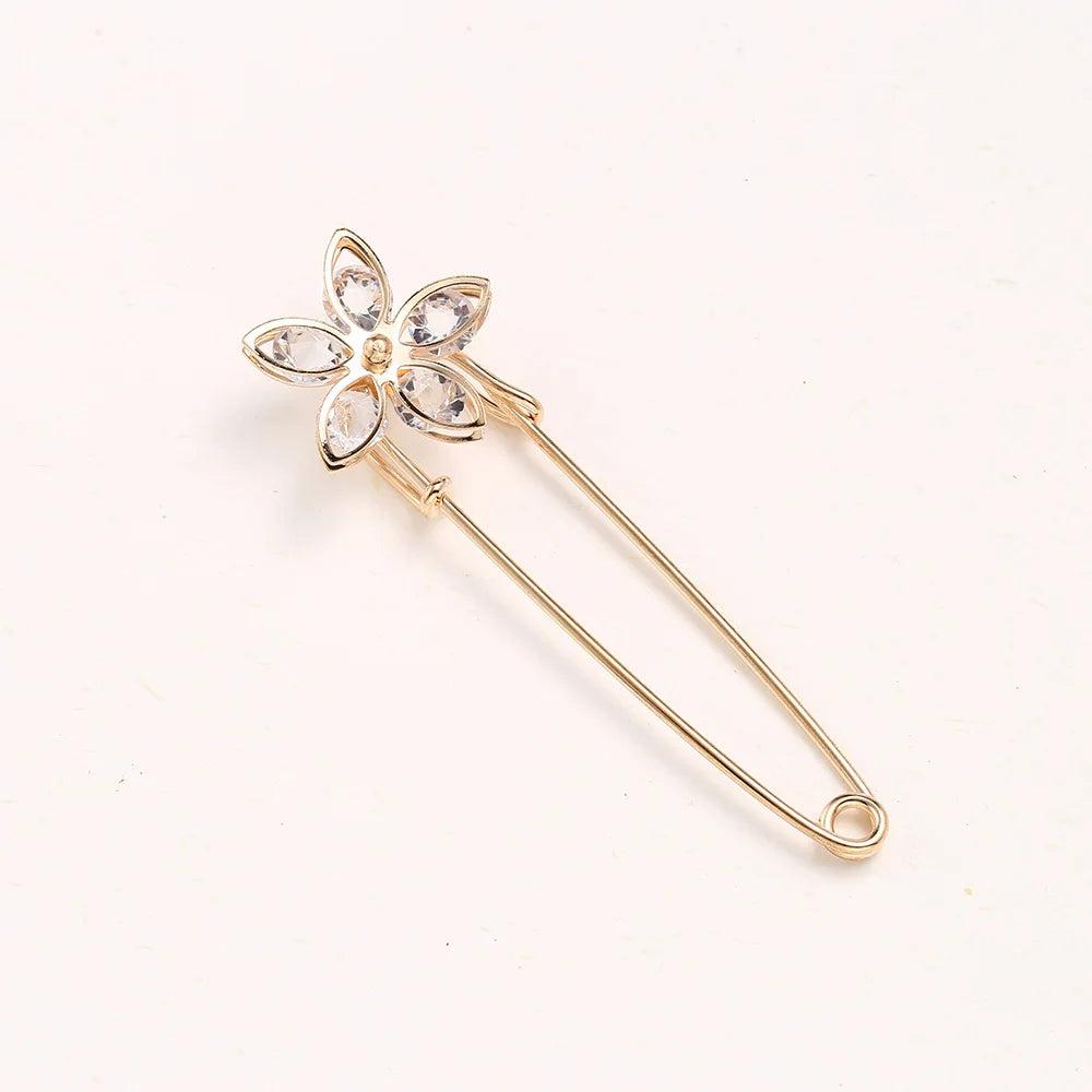 A delicate gold adjustable pearl brooch shaped like a flower with clear stones.