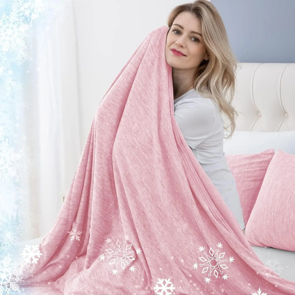 A woman models a pink quilted blanket with white snowflake patterns in a bright room.