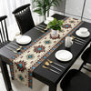 A black dining table set with a bohemian linen table runner featuring an Indian-inspired geometric print.
