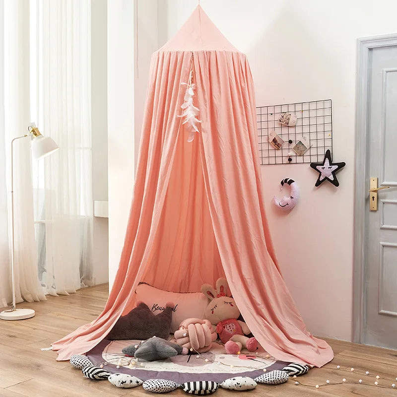 A pink princess hanging bed canopy for kids with a white feather decoration and soft fabric draping.