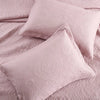 A set of pink embroidered cotton quilted pillow covers resting on a pink quilted fabric.