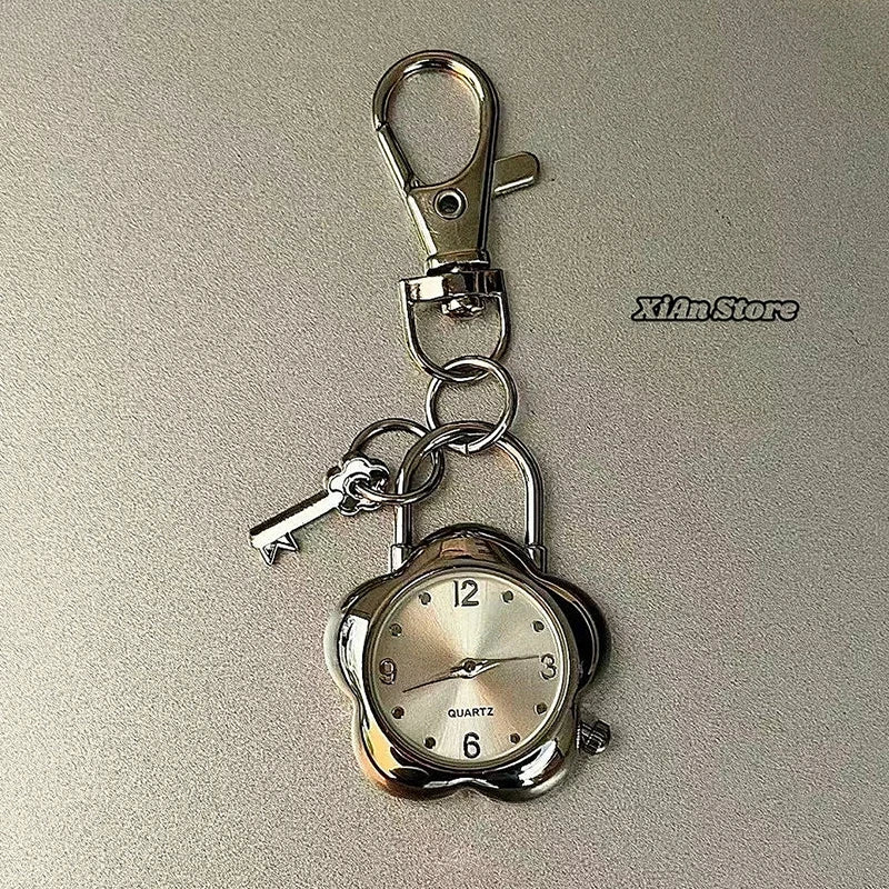 A silver quartz pocket watch is attached to a metal keychain with a clasp.