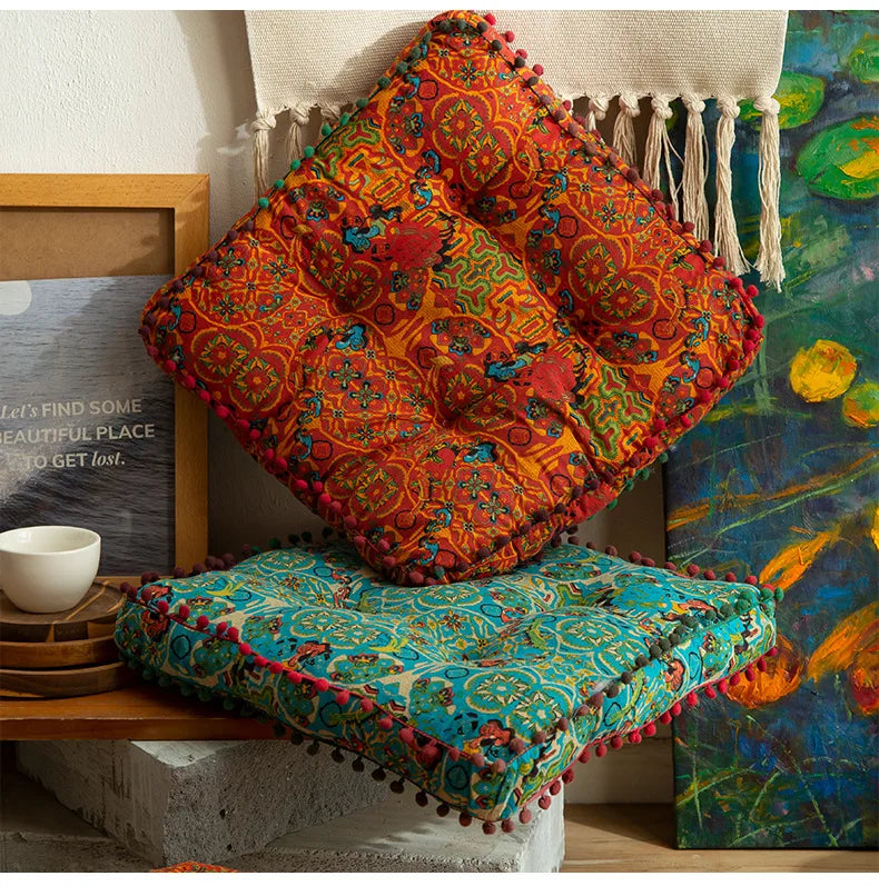 A vibrant orange and red bohemian cotton linen throw cushion resting on a wooden shelf.