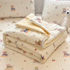 A stack of light beige quilted blankets with embroidered animals and stars resting on a patterned surface.