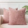 A close-up of a textured, dusty rose boucle throw pillow cover resting on a light-colored sofa.