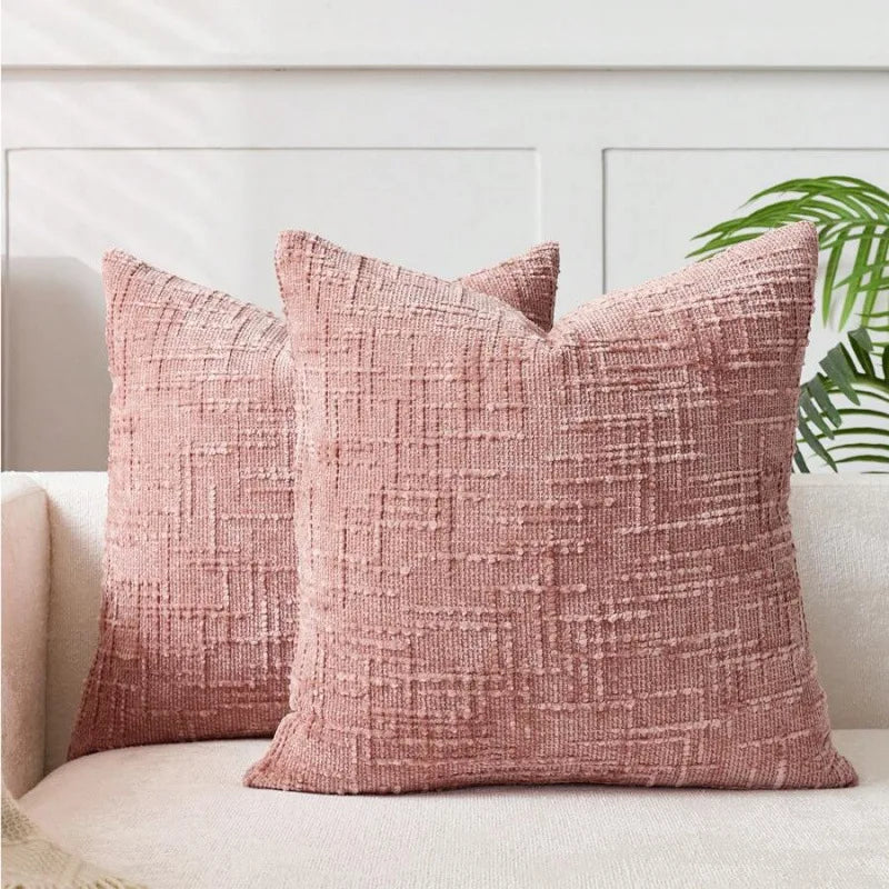 A close-up of a textured, dusty rose boucle throw pillow cover resting on a light-colored sofa.