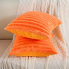 Orange and yellow ribbed faux rabbit fur cushion cover resting on a white textured fabric.