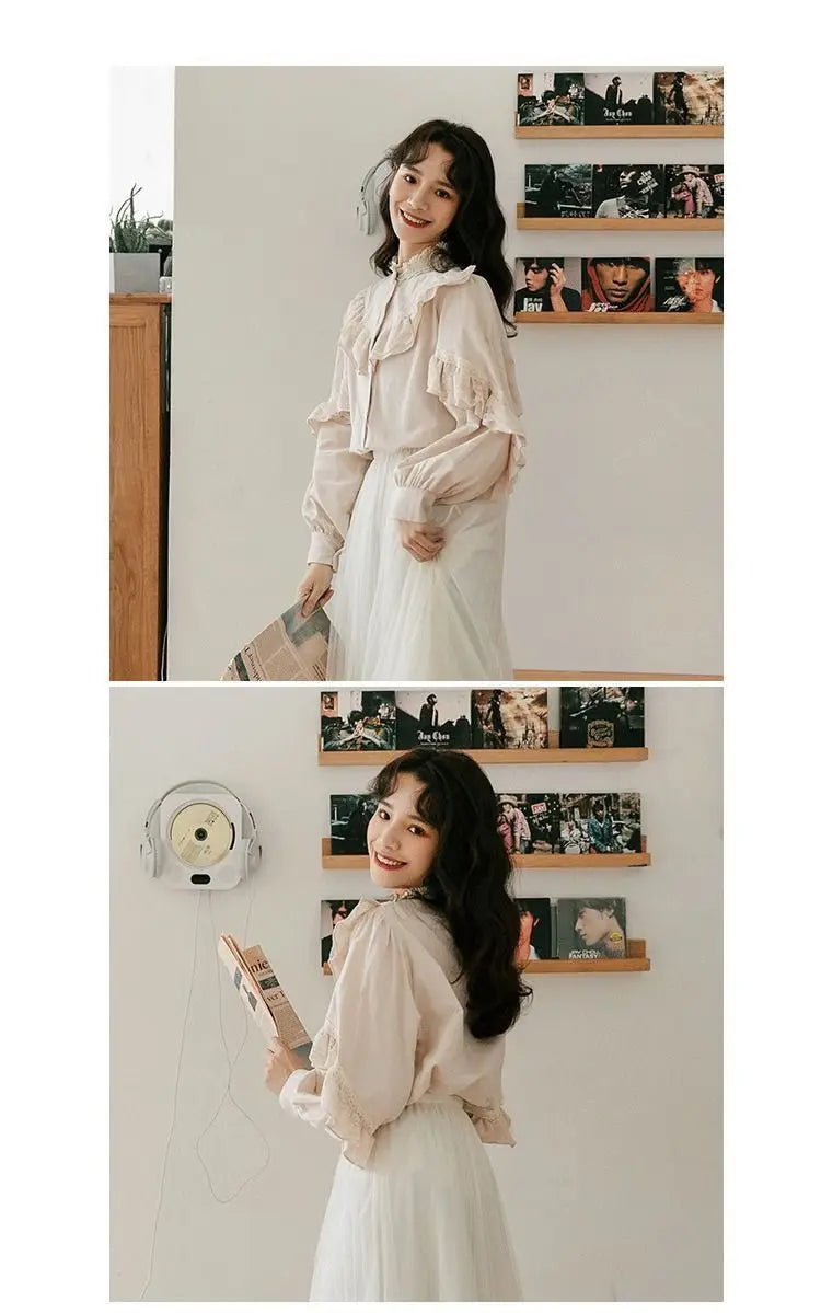 A woman models a cream-colored retro lace long sleeve blouse and white skirt against a light gray wall with framed photos.
