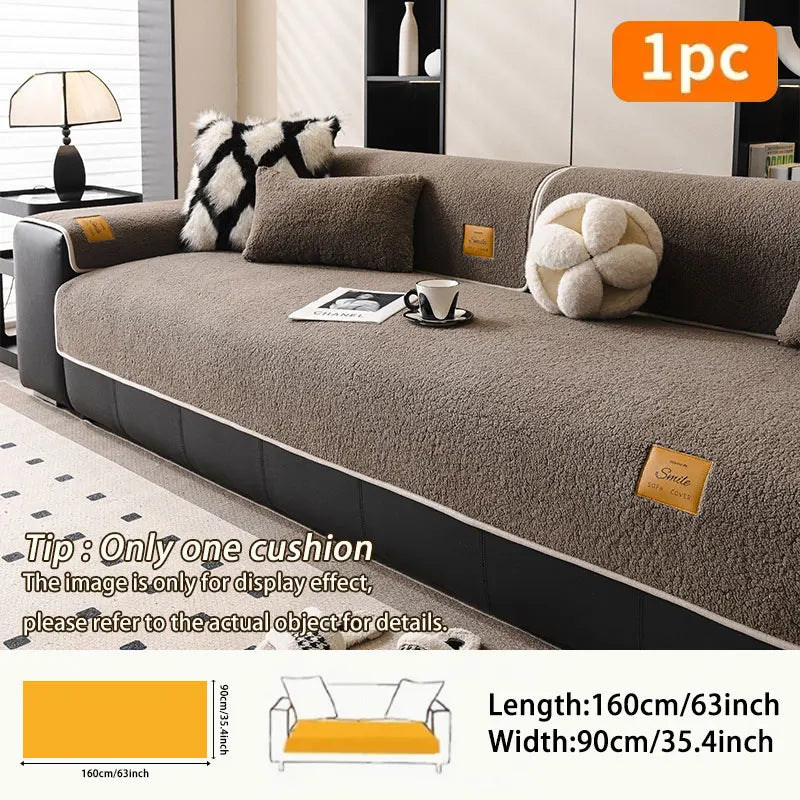 A beige fleece sofa mat with a cushion and decorative pillows displayed on a modern sofa.