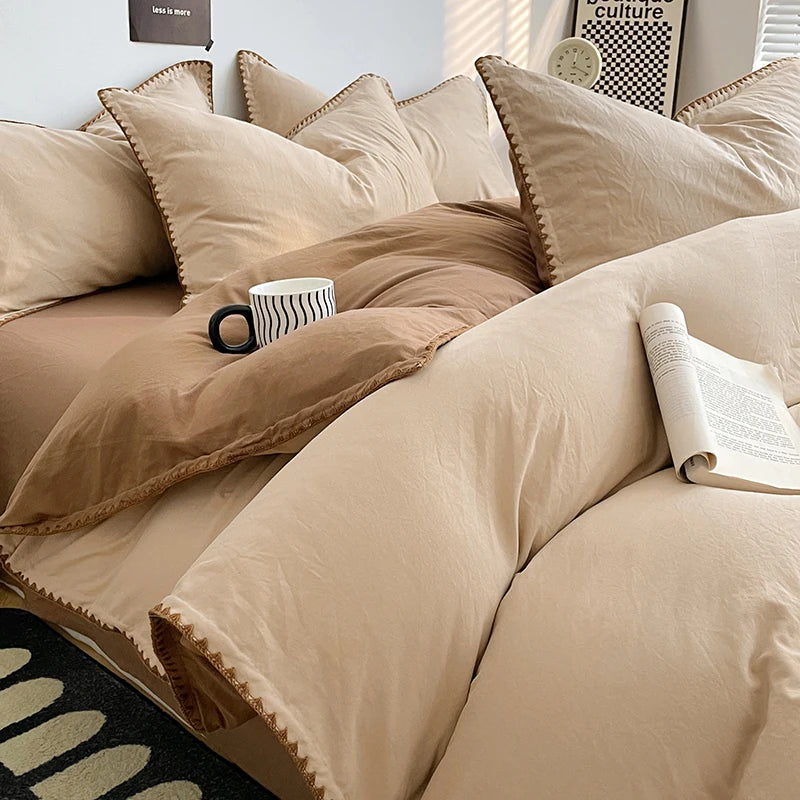 A close-up of a beige luxurious washed cotton bed linen set featuring neutral tones and decorative stitching.