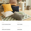 A set of plaid cushion covers in various shades of green and gray displayed on a light wooden floor.
