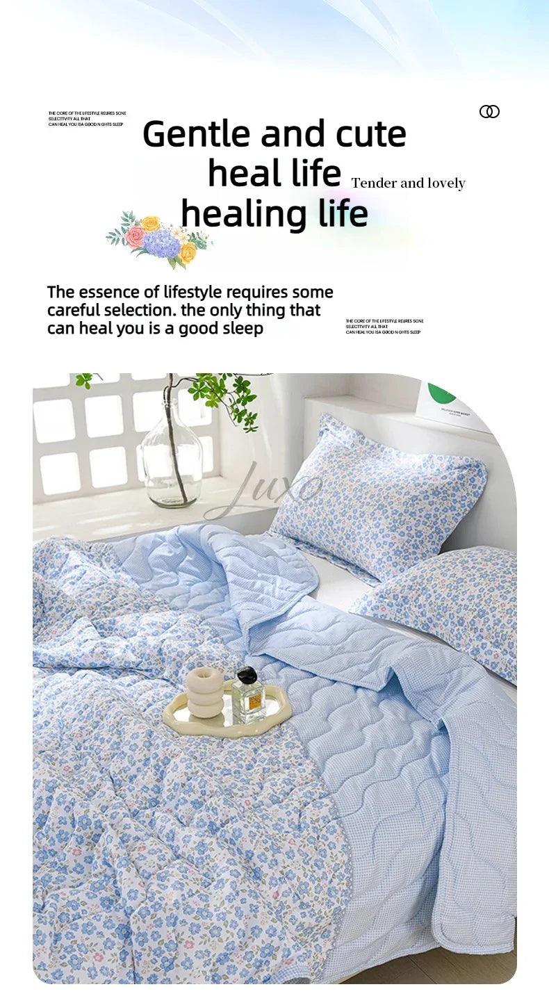 A light blue quilted quilt set with a floral pattern is displayed on a bed, emphasizing gentle and healing life.