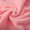 A close-up of pink coral velvet cleaning face towels folded into a swirl.