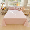 A pink gingham flat sheet and pillow set is displayed on a bed in a bright room with a window.