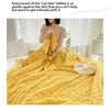 A thick yellow fleece blanket is draped on a bed, showing its soft texture and warmth.