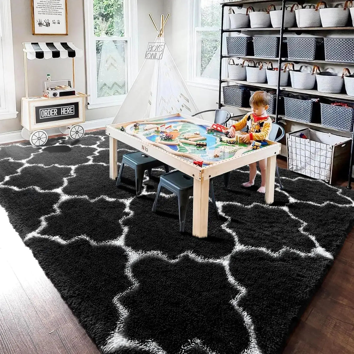 A geometric plush area rug with white and black patterns is displayed in a living room setting.