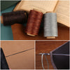 A close-up of waxed threads in various colors and a sewing needle kit on brown paper.