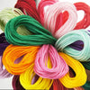 A vibrant bundle of multicolor embroidery floss threads in various shades including red, pink, green, yellow, and purple.