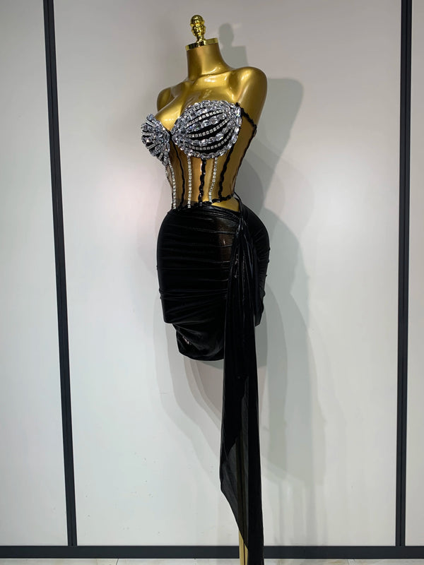 A mannequin displays a sparkly diamond two-piece performance set featuring embellished top and a black draped skirt.