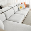 A white jacquard elastic sofa cushion slipcover with orange accent pillows on a light-colored sofa.