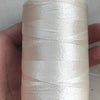 A spool of white high tenacity polyester sewing thread is held in a hand, with a yellow plastic core visible.