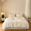 A fluffy cream faux fur throw blanket is displayed on a bed with soft lighting.