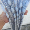 A hand holds a vertical arrangement of light blue fuzzy fringe strands with silver glitter for home decor.