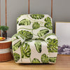 A cream-colored recliner or sofa slipcover featuring a vibrant green tropical leaf print.