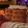 A close-up of two textured brown chenille throw pillows resting on a light-colored sofa with a knitted blanket.