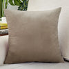 A square, taupe velvet cushion cover resting on a light-colored sofa.