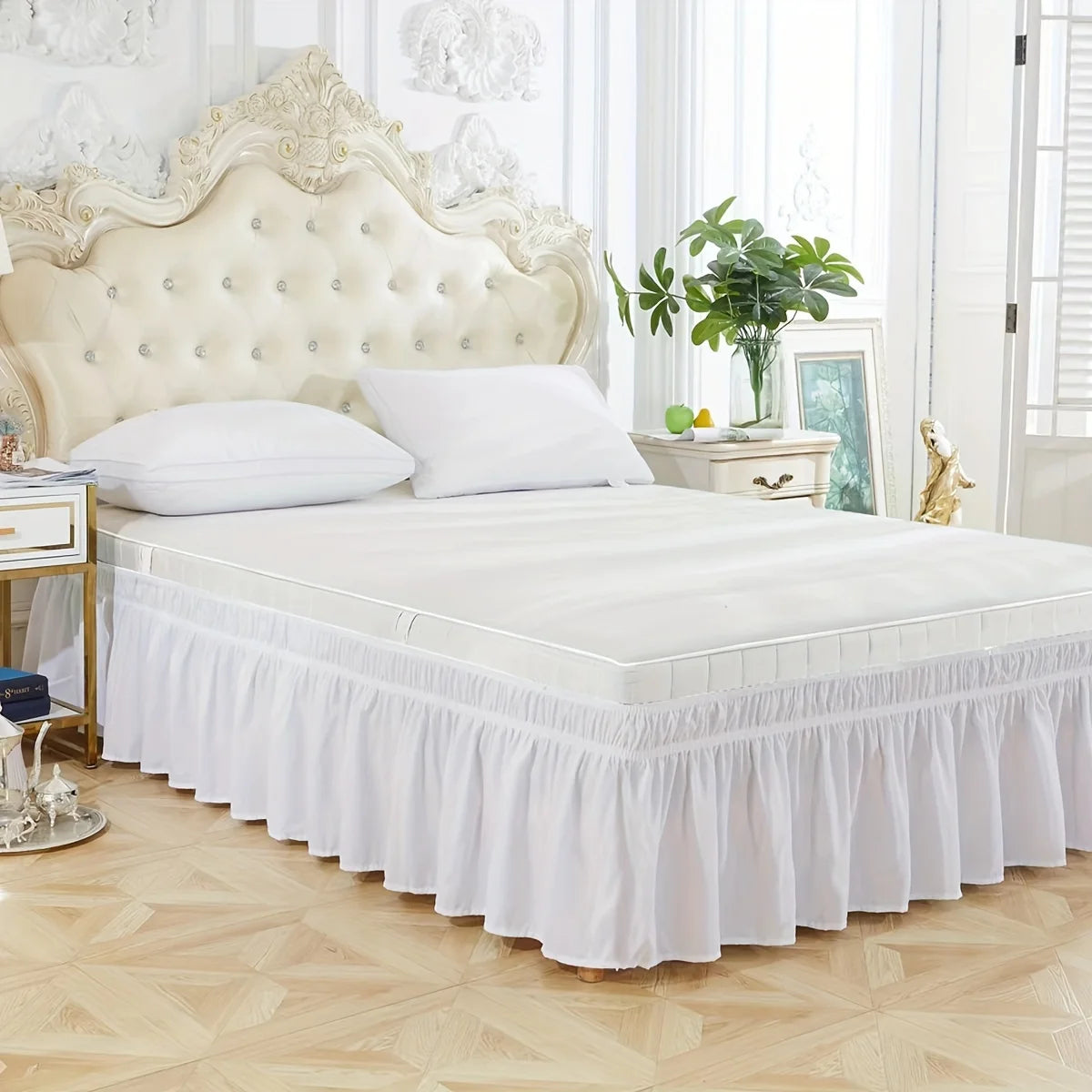White adjustable elastic bed skirt with ruffle trim on a white upholstered headboard and bedding.