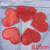 Five red glitter heart patches sewn onto a denim fabric.