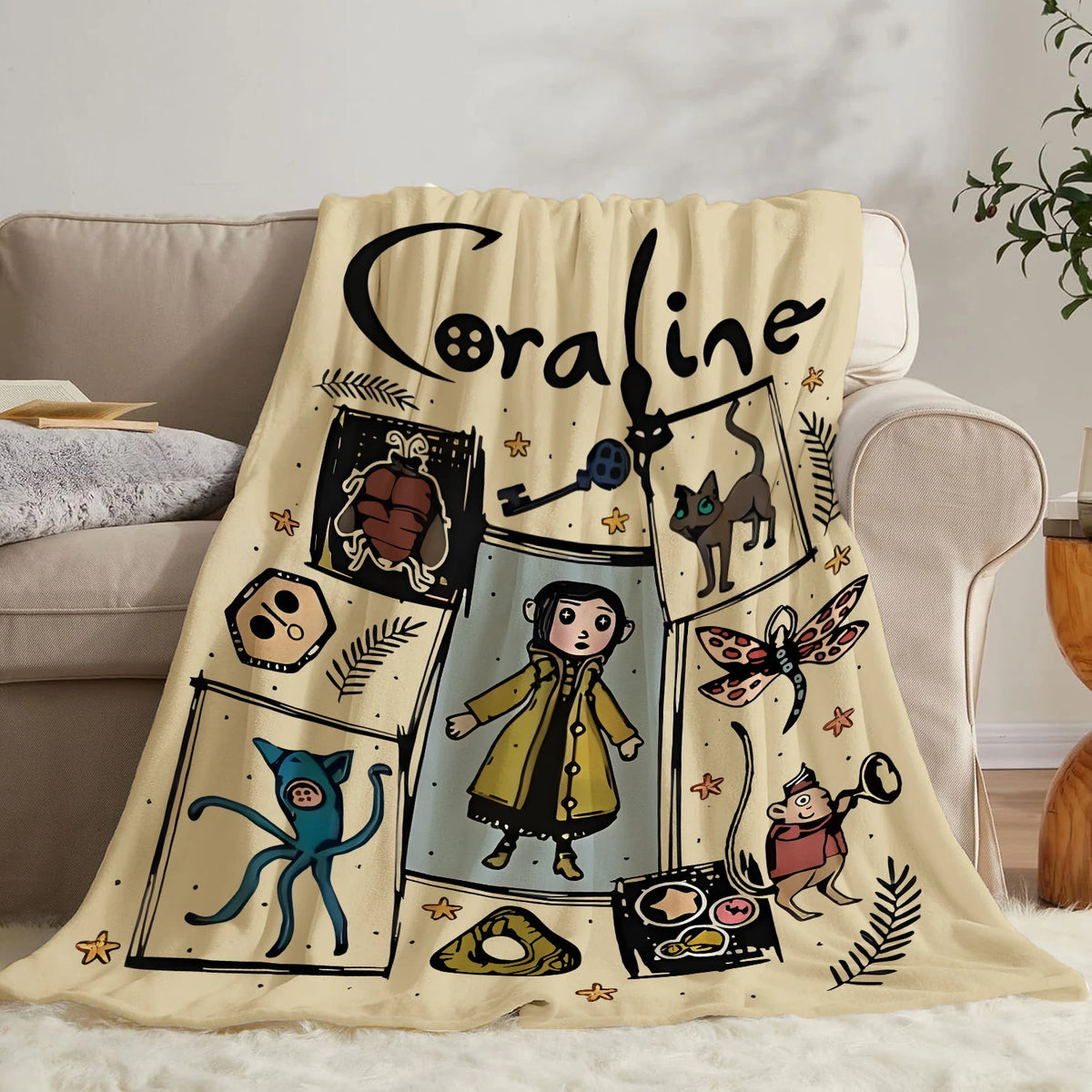 A beige flannel throw blanket featuring a black script name and various illustrated characters on a light background.