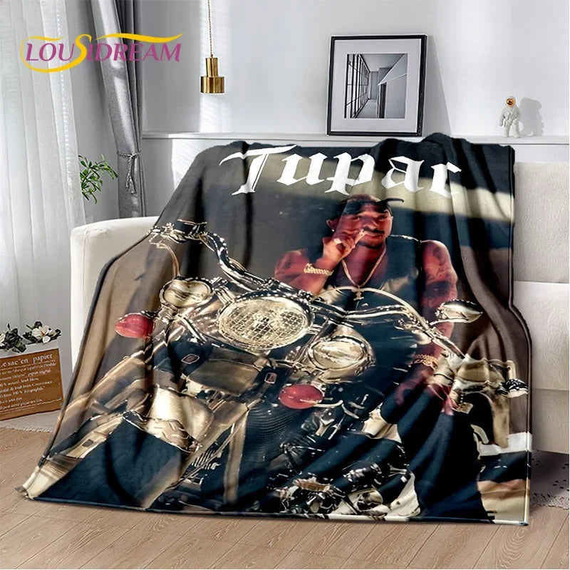 A dark graphic throw blanket featuring a vintage-inspired portrait of Tupac Shakur.
