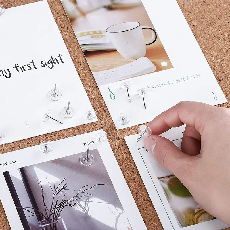 A hand is placing a transparent round head push pin into a card featuring a photo and text.