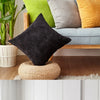 A collection of textured cushion covers in various shades of green, gray, and yellow displayed on a wooden sofa.