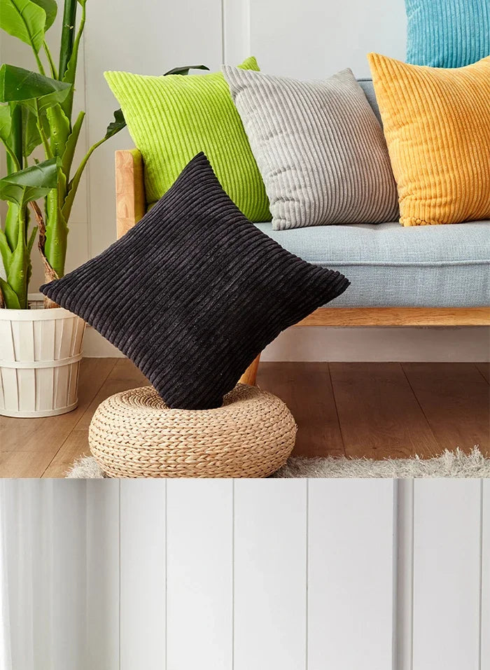 A collection of textured cushion covers in various shades of green, gray, and yellow displayed on a wooden sofa.