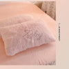 A fluffy pink faux fur pillow resting on a light pink duvet cover.