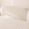 A cream-colored sofa cover with a textured, quilted white fabric draped over the back.